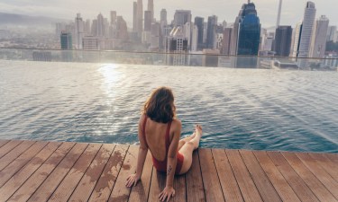 Young Caucasian woman in the swimming pool with view of Kuala Lumpur