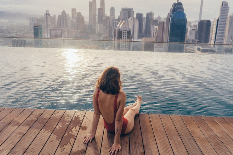 Young Caucasian woman in the swimming pool with view of Kuala Lumpur